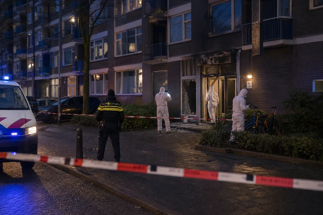 AI-foto van een realistische Amsterdamse woonstraat in de avond met forensisch onderzoekers, politielint en schade aan een flatentree als beeld bij de nieuwe OM-verdenking na een explosie.