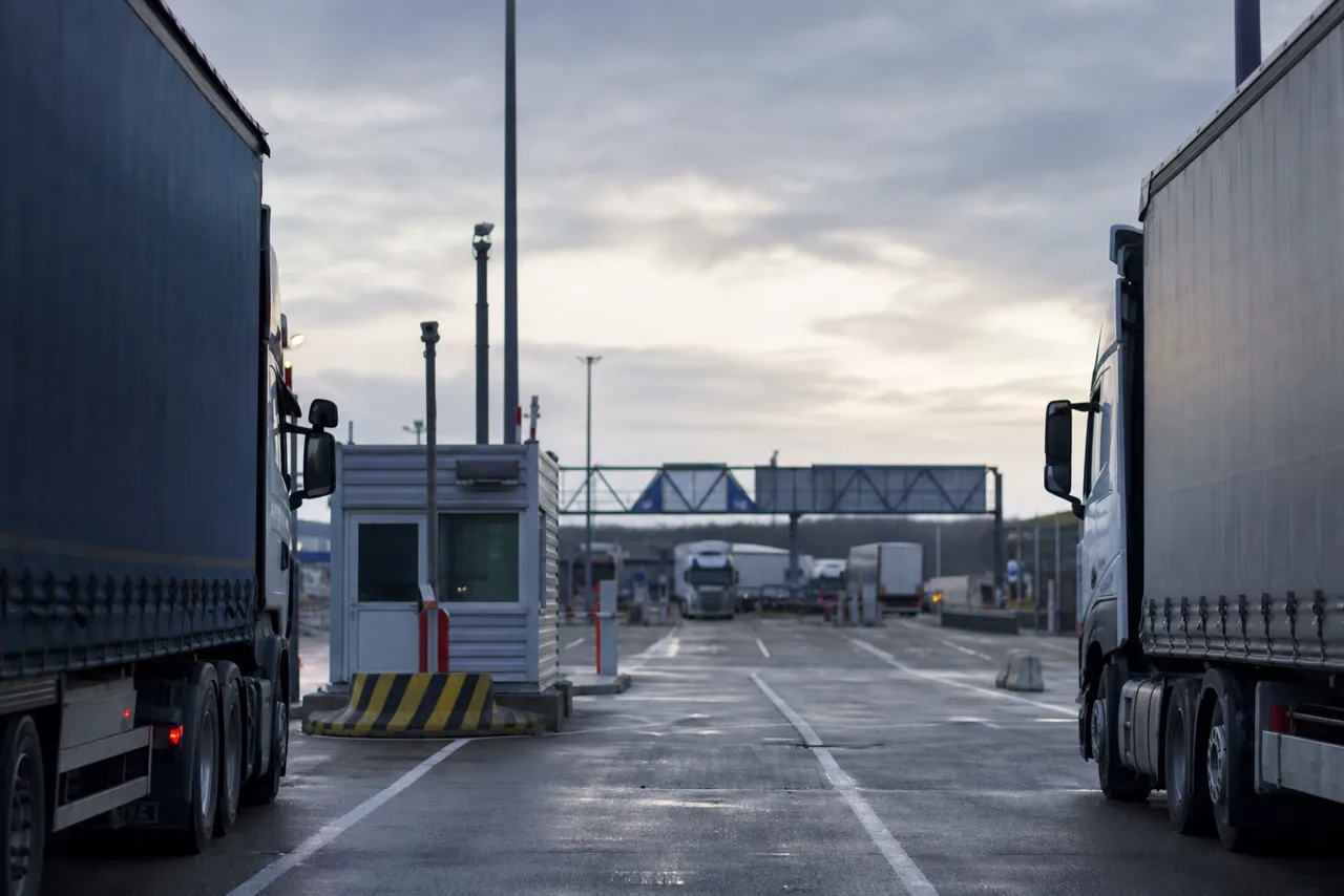 Vrachtwagens wachten bij een ferryterminal met douane-infrastructuur.