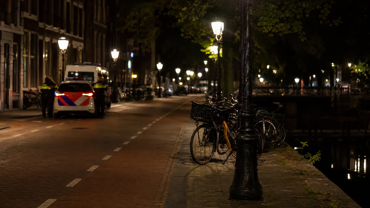 AI-foto van een rustige Nederlandse stadsstraat in de avond met fietsen en een politieauto in de verte als beeld bij een analyse over veiligheid en opsporing.