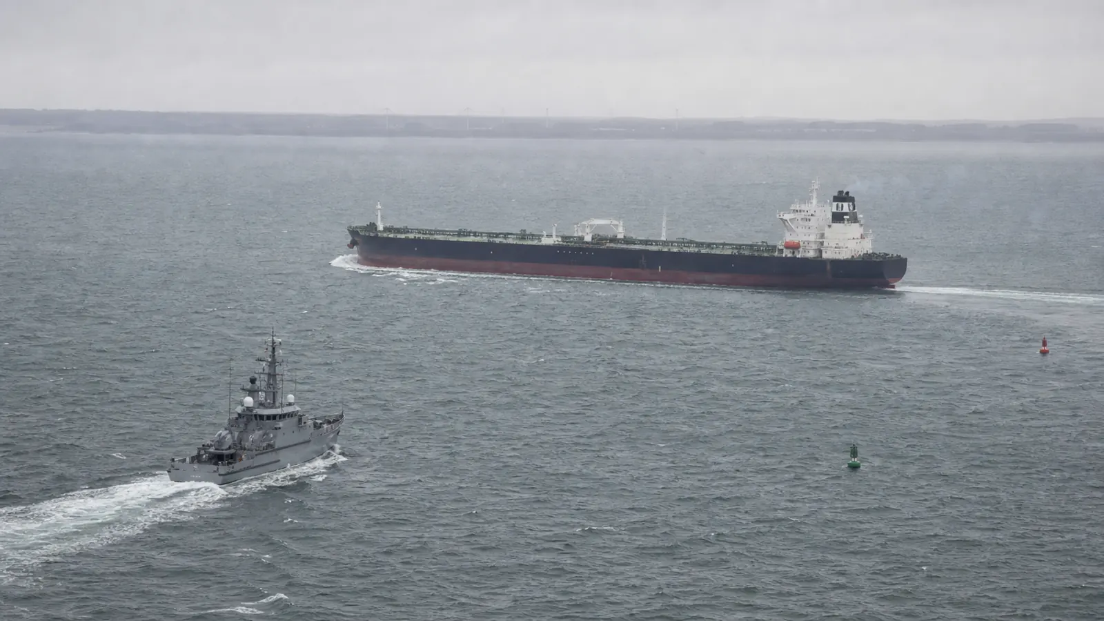AI-beeld van een anonieme olietanker op grijze zee met een patrouillevaartuig op afstand als illustratie bij Europese acties tegen de Russische schaduwvloot.